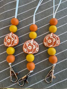 three orange and yellow beaded necklaces with pumpkin decorations on them sitting on a table