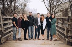 a group of people standing next to each other in front of a wooden fence on a bridge