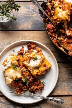 a white plate topped with lasagna next to a casserole covered in cheese