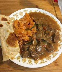 a white plate topped with meat and veggies next to a tortilla