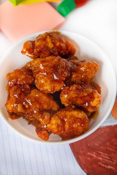 a white bowl filled with fried chicken on top of a table next to colorful blocks