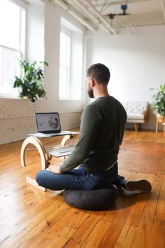 a man sitting on the floor with his laptop in front of him and looking at the screen