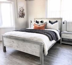 a white bed sitting in a bedroom on top of a hard wood floor next to a window