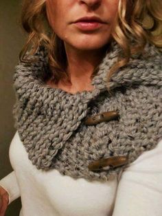 a woman with blonde hair wearing a gray knitted cowl scarf and white sweater