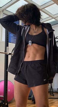 a woman standing in front of a mirror wearing black shorts and a sports bra top