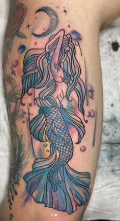 a woman's arm with a mermaid tattoo on it