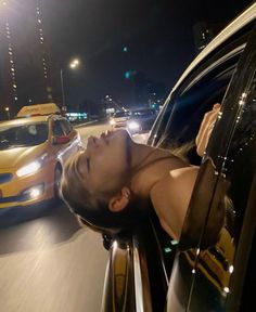 a woman is leaning out the window of a car at night with her head sticking out