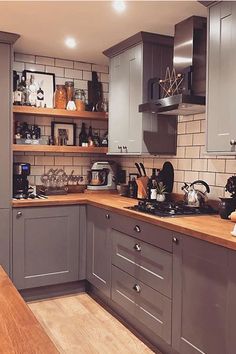 a kitchen with gray cabinets and wooden counter tops