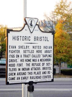 a historical sign on a pole in front of a street