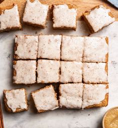 there are many pieces of bread with icing on it next to some dipping sauce