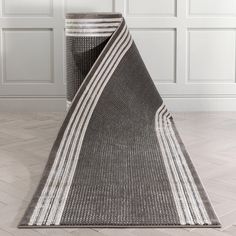 an area rug on the floor in front of a white wall