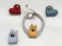 three different types of cell phones and cords on a white surface with two cats, one cat ear plugged into the charger