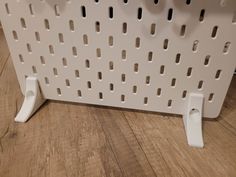 a close up of a wall mounted shelf on a wooden floor with holes in it