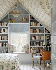 an attic bedroom with built in bookshelves and a window seat that has a chandelier hanging from the ceiling