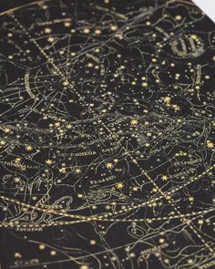 a close up of a star map with gold stars on black paper and white background