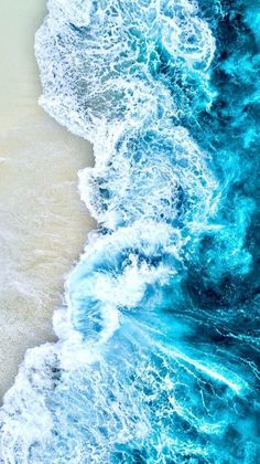 an aerial view of the ocean waves and sand