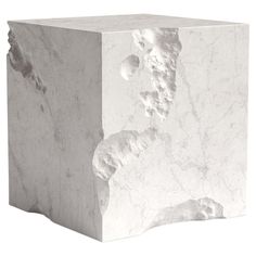 a white marble block that is shaped like a cube with some rocks on the side