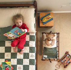 a little boy laying in bed reading a book to his teddy bear and other toys