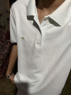 a man wearing a white polo shirt is holding his hands in his pockets