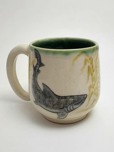 a ceramic mug with a whale design on the outside and inside, sitting on a white surface