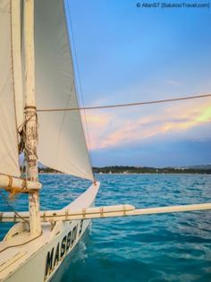 a sailboat is sailing in the ocean at sunset