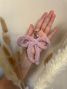 a hand is holding some kind of pink object in it's palm area with feathers