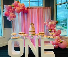 a table topped with cake and pink balloons