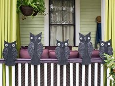 four black cats sitting on top of a window sill in front of a house