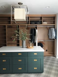 an open closet with green drawers and white counter top, next to a shelf filled with clothes