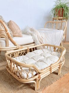 a wicker couch and chair sitting next to each other on a rug in front of a white wall