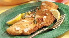 a green plate topped with fried fish and lemon wedges