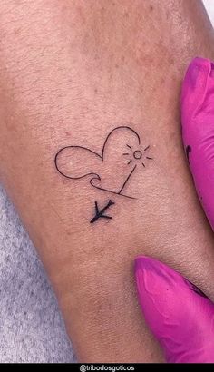 a woman's arm with a small heart and an arrow tattoo on the wrist