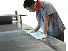 a man in grey shirt and white gloves working on a conveyor belt