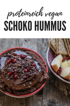 two bowls filled with chocolate hummus next to crackers and apples on a wooden table