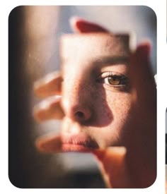 a woman looking in the mirror with her hand on her face and one eye open