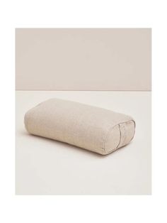 a pillow that is sitting on top of a white surface with a light colored background