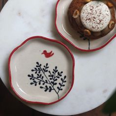 two plates with designs on them are sitting on a white table top, one has a small piece of cake in the middle