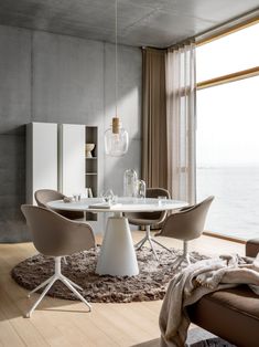 a white table and chairs in a room next to a large window with an ocean view