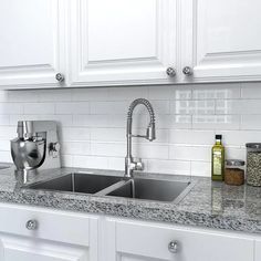 a kitchen with white cabinets and granite counter tops, stainless steel faucet sink and soap dispenser