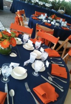 the table is set with orange napkins and silverware