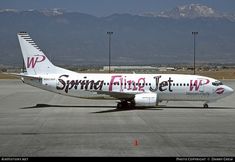 a large jetliner sitting on top of an airport tarmac with mountains in the background