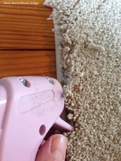 a person is using a pink sprayer to clean the carpet on top of a wooden floor