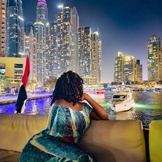 a woman sitting on top of a couch next to a body of water at night