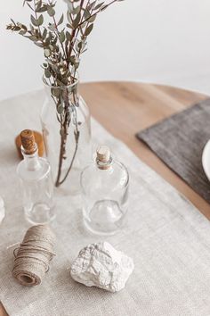 the table is set with glass bottles and twine spools