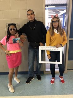 three people standing next to each other in front of a wall with a sign on it