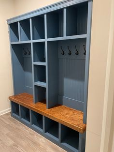 an empty room with several blue shelves and hooks on the wall, along with wood flooring