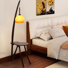 a white bed sitting next to a wooden floor lamp