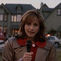 a woman holding a microphone in front of a house