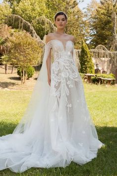 a woman in a wedding dress standing on the grass