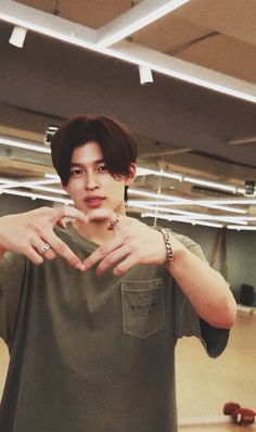 a young man making a heart sign with his hands while standing in an empty room